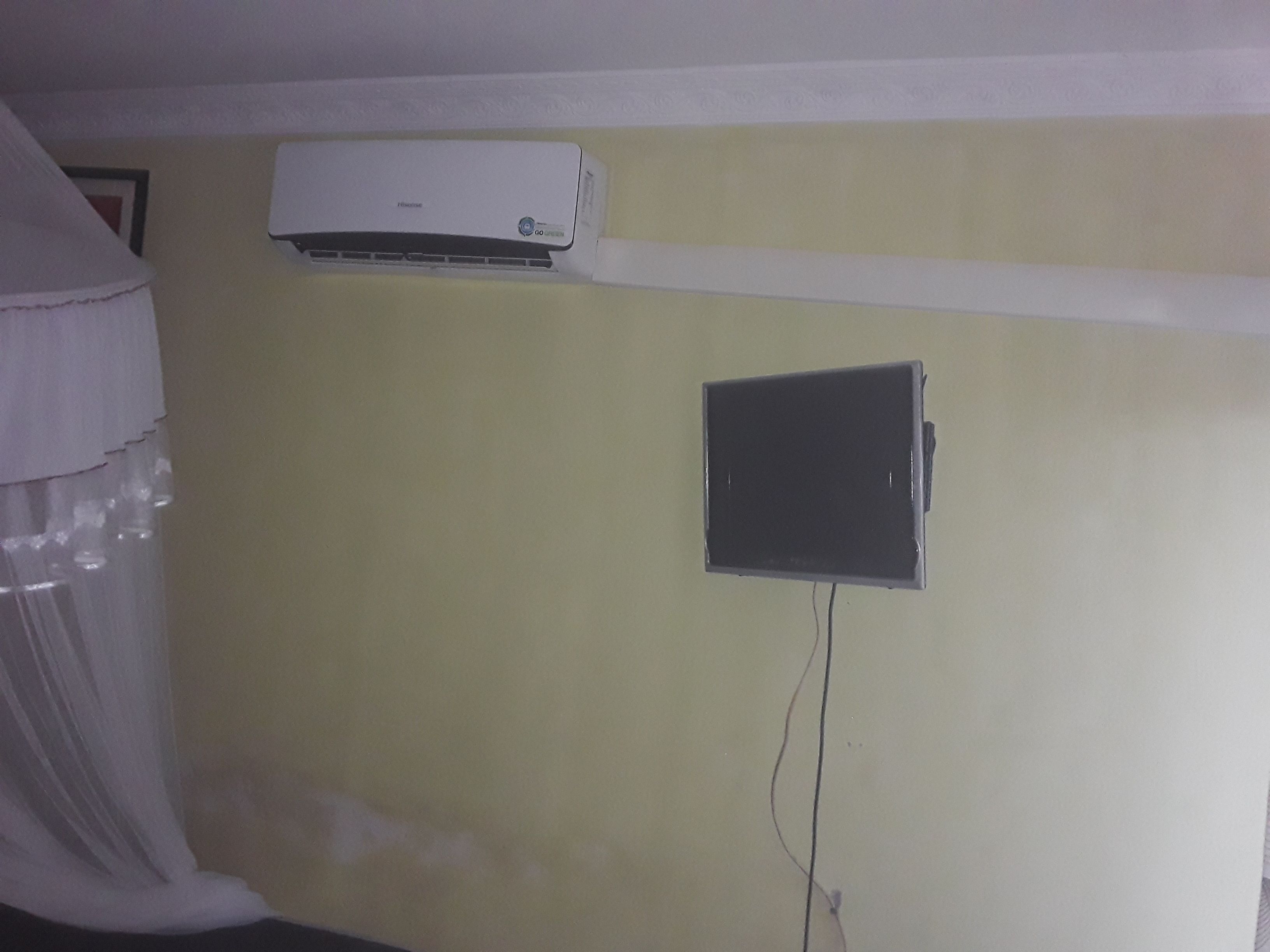 Habitación con aire acondicionado de pared y un pequeño televisor.