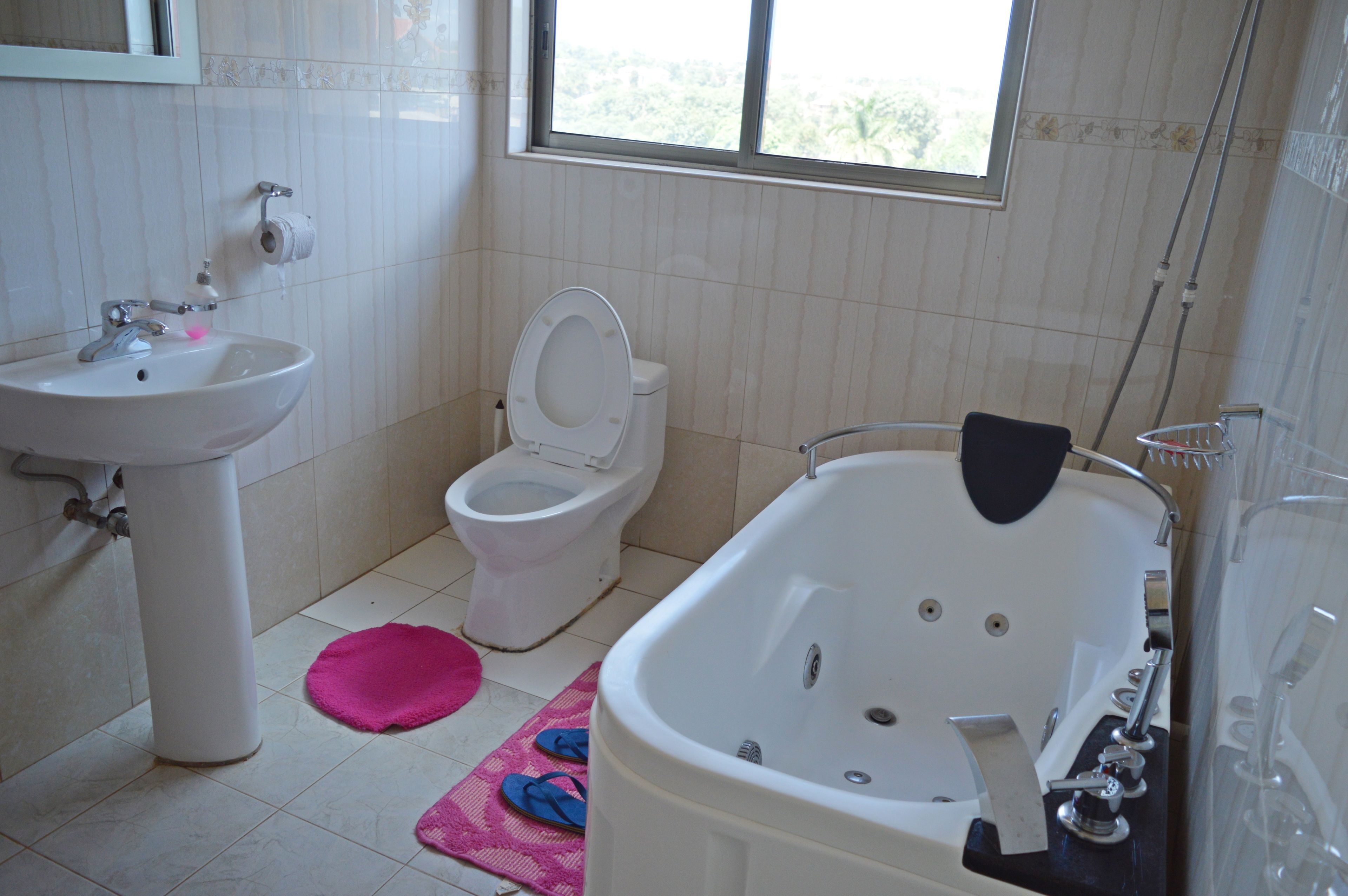 Baño con lavamanos, inodoro, bañera y ventana que proporciona luz natural.