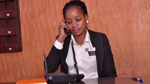 A reception desk with a name tag, a phone, and a pen. - Unik Hotel Limited (Kampala)