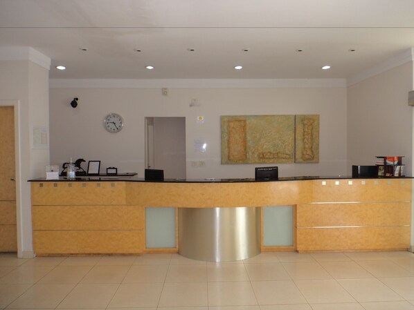 A reception desk with a clock, a wall-mounted painting, and a door leading to another room. - Di Giulio Hotel (São José dos Campos)