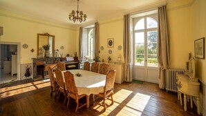 A dining room with a large table, chairs, a piano, and a chandelier. - La Maison de Maître (Fontenay-le-Comte)