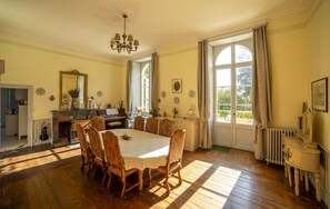 A dining room with a large table, chairs, a piano, and a chandelier. - La Maison de Maître (Fontenay-le-Comte)