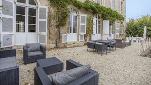 An outdoor patio with wicker furniture, a table, and chairs. - La Maison de Maître (Fontenay-le-Comte)