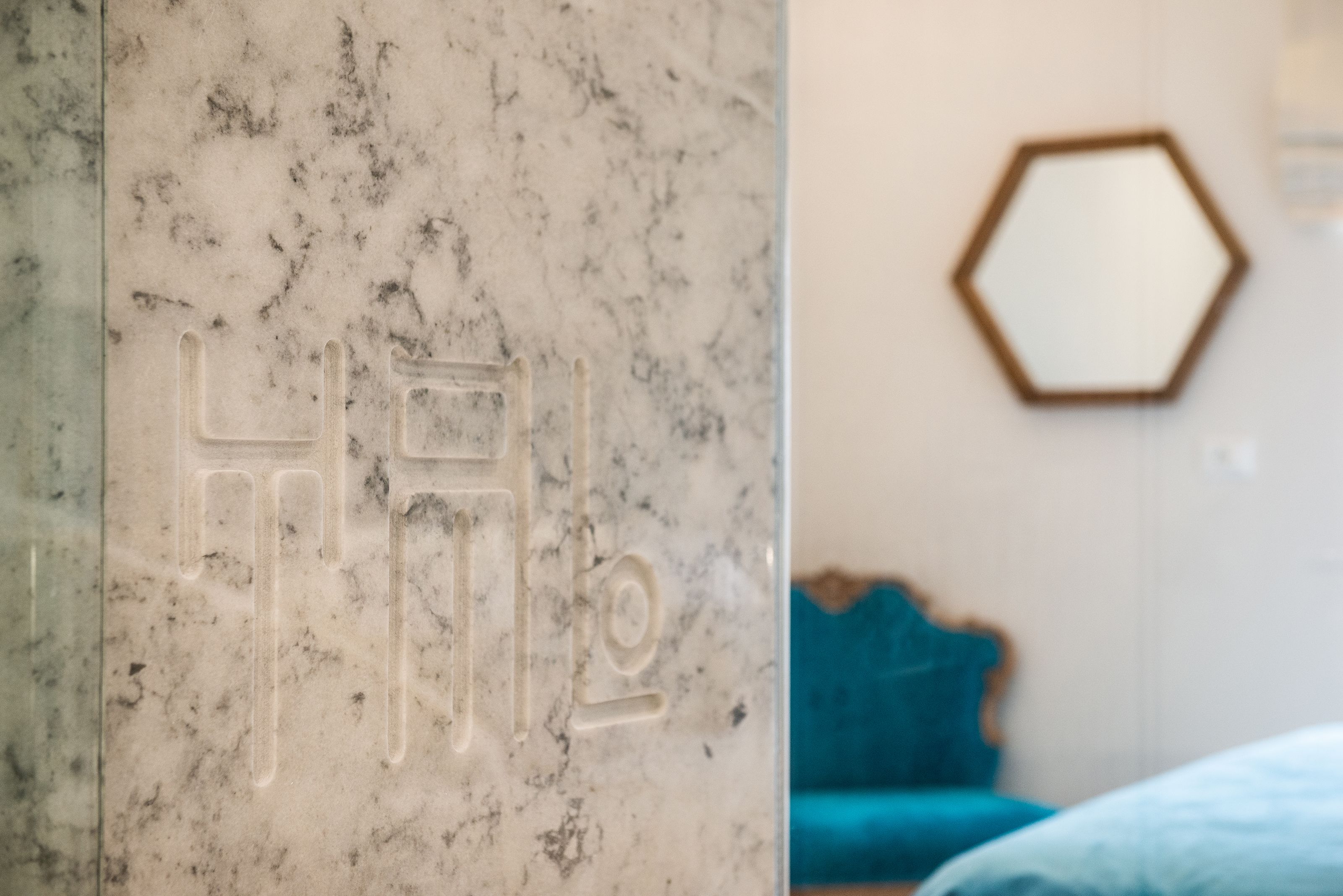 A marble wall with a logo and a hexagonal mirror on the wall.