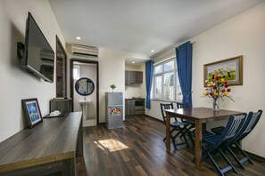 A modern kitchen with a built-in oven, a refrigerator, and a dining area with a wooden table and chairs. - Alibaba Hotel (Da Nang)