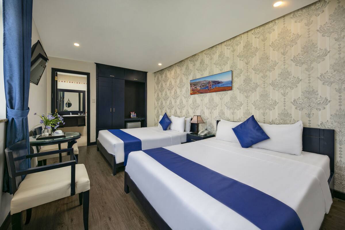 A hotel room with two beds, a desk, and a chair.
