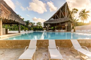 Una piscina al aire libre, sillones reclinables de piscina