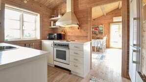 Uma cozinha compacta com fogão, micro-ondas e pia. Há uma área de jantar com mesa e cadeiras.
