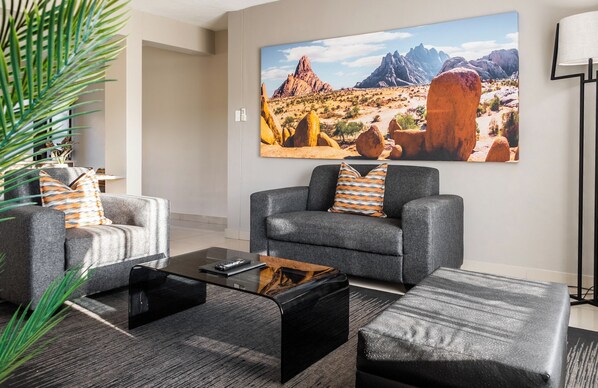 A living room with two grey sofas, a coffee table, and a large desert landscape painting on the wall.