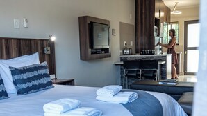 A hotel room with a bed, a desk, a microwave, and a person in the background. - Hillside Executive Accommodation (Windhoek)