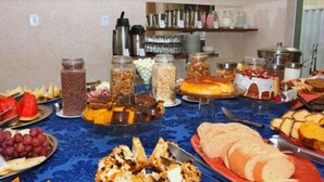 A buffet table with various food items and utensils. - Pousada Águas do Forte (Cabo Frio)