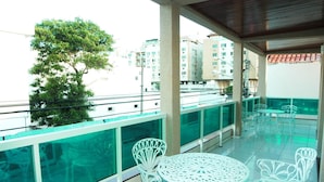 A balcony with white chairs and a table, overlooking a cityscape with buildings. - Pousada Águas do Forte (Cabo Frio)