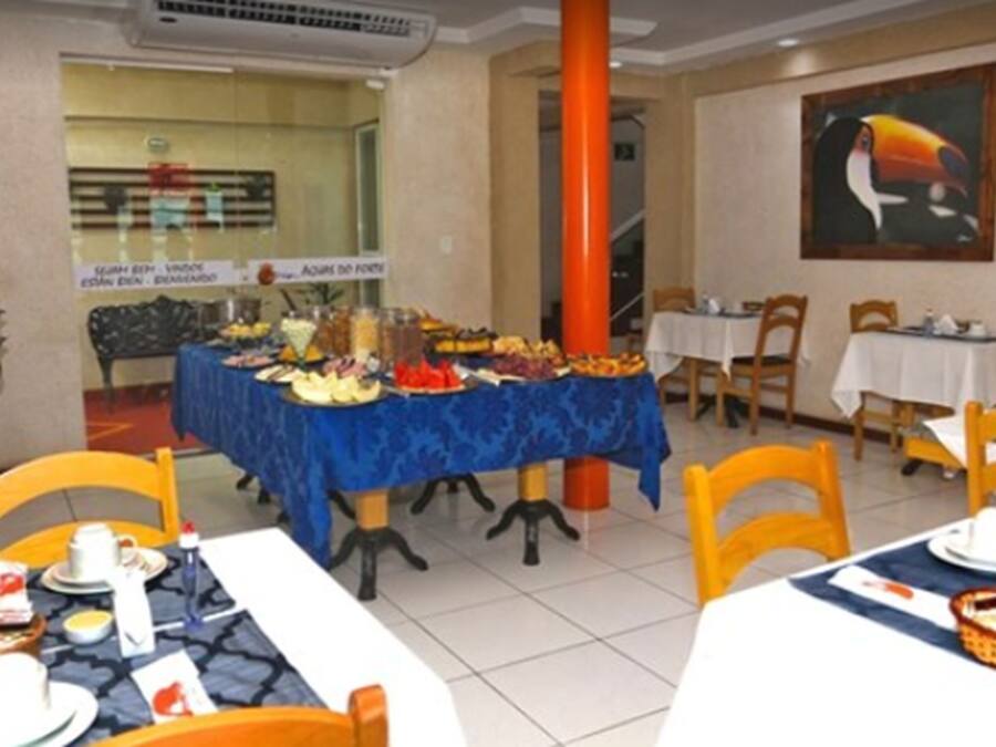A dining area with tables set for breakfast, a buffet with various food items, and a large painting on the wall.