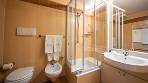 A bathroom with a toilet, bidet, glass-enclosed shower, and a sink. - Piazzi House (Sondrio)
