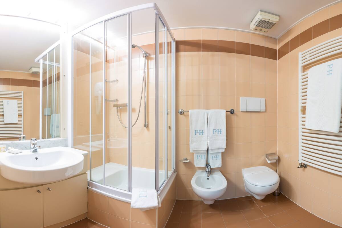 A bathroom with a glass-enclosed shower, a sink, a bidet, and a toilet.