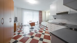 A modern kitchen with a checkered floor, white cabinets, and a dining area with a table and chairs. - Piazzi House (Sondrio)