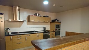 Una cocina con armarios de madera, una campana extractora de acero inoxidable, un microondas y una encimera de ladrillo.