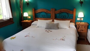 Una cama bien hecha con ropa de cama blanca y diseños florales, dos mesitas de noche con lámparas y un cabecero de madera.