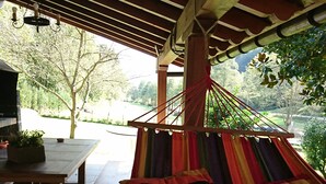 Una hamaca bajo una pérgola de madera con vista a un parque.