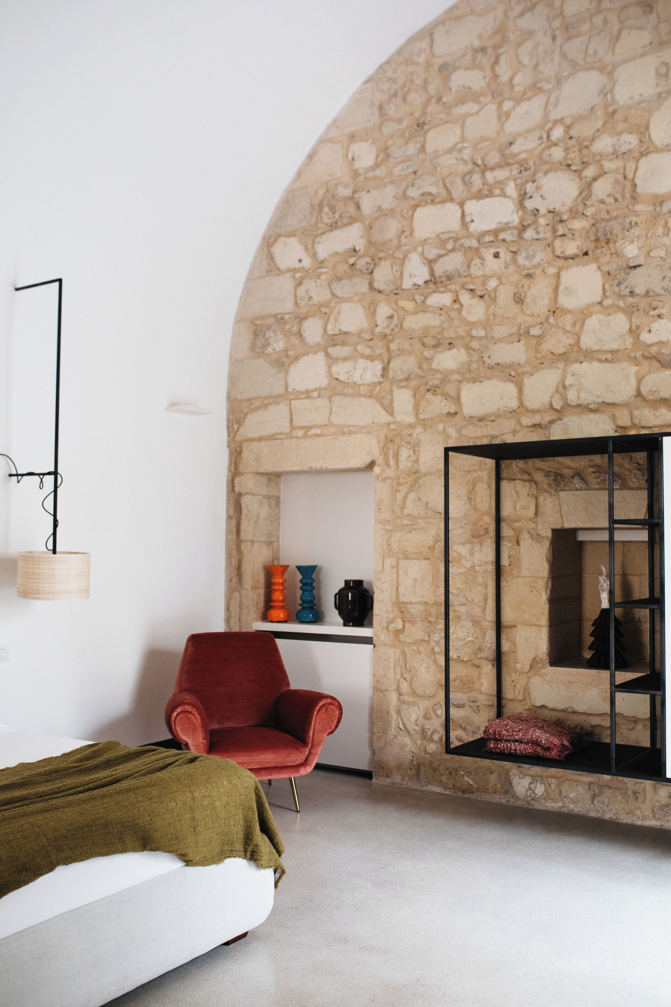 Ein Zimmer mit Steinwand, einem roten Sessel, einem weißen Sofa und einem Kamin.