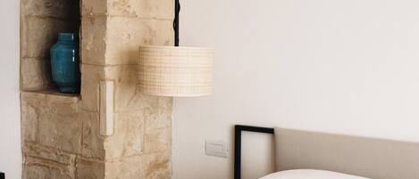Quarto com lareira de pedra, luminária pendente e cama com manta azul-turquesa.