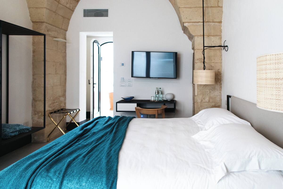 A bedroom with a bed, a desk, and a TV.