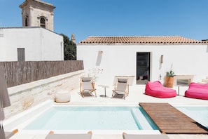 A rooftop pool area with lounge chairs, a wooden deck, and a white building with a tiled roof. - Palazzo De Noha (Lecce)
