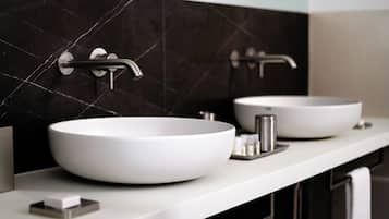 A modern bathroom with two white sinks, a black tiled backsplash, and a white countertop.