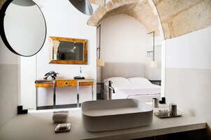 Um banheiro moderno com um espelho grande, um aparador de madeira, uma cama e um arco de pedra.