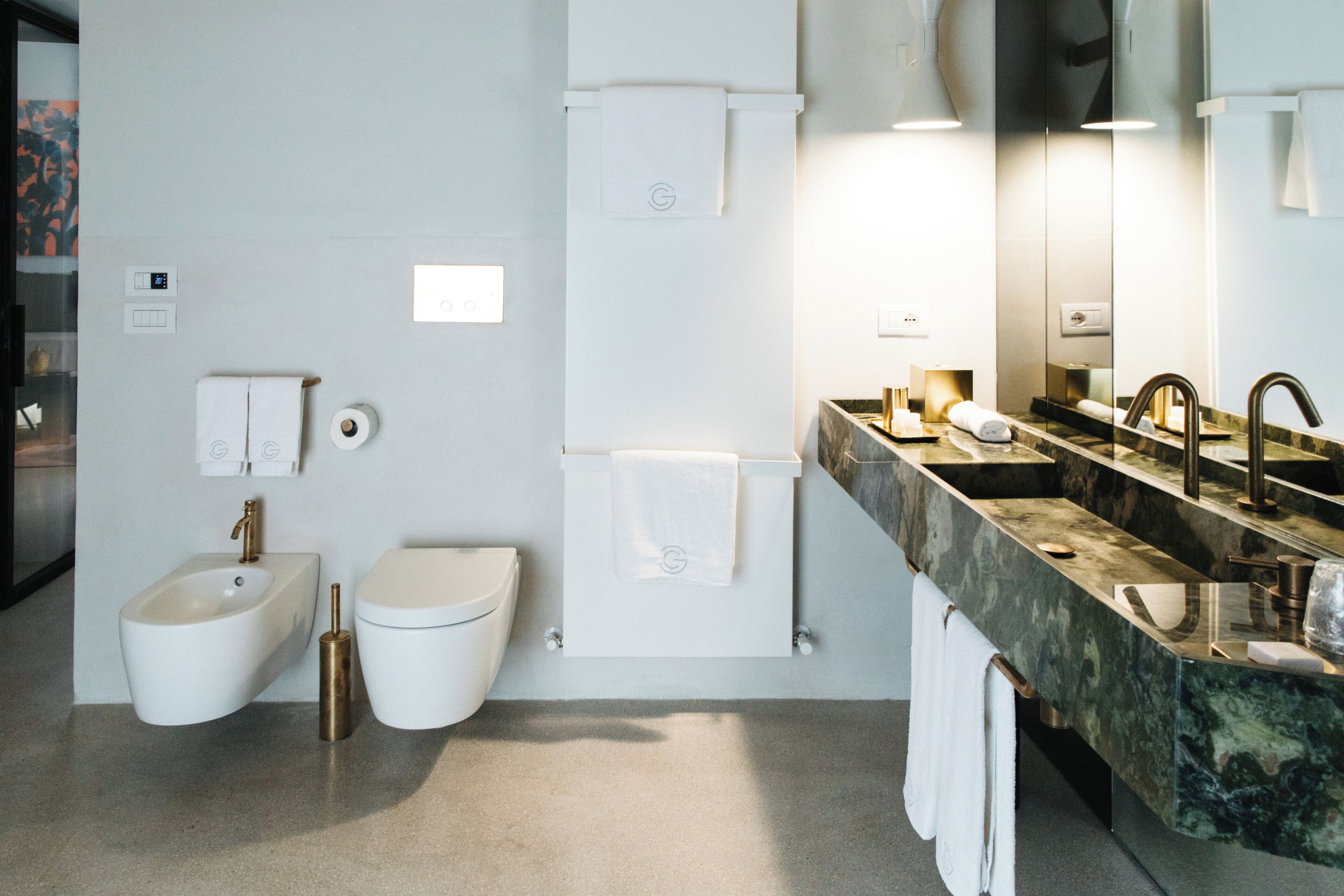 Un baño moderno con bidé, inodoro, lavamanos y un espejo grande.