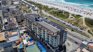 Ein Hochhaus-Hotel mit mehreren Etagen, einem Dachpool und Blick auf Strand und Meer.