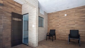 Ein modernes Interieur mit Holzwandverkleidung, einer Glastür und zwei schwarzen Stühlen.
