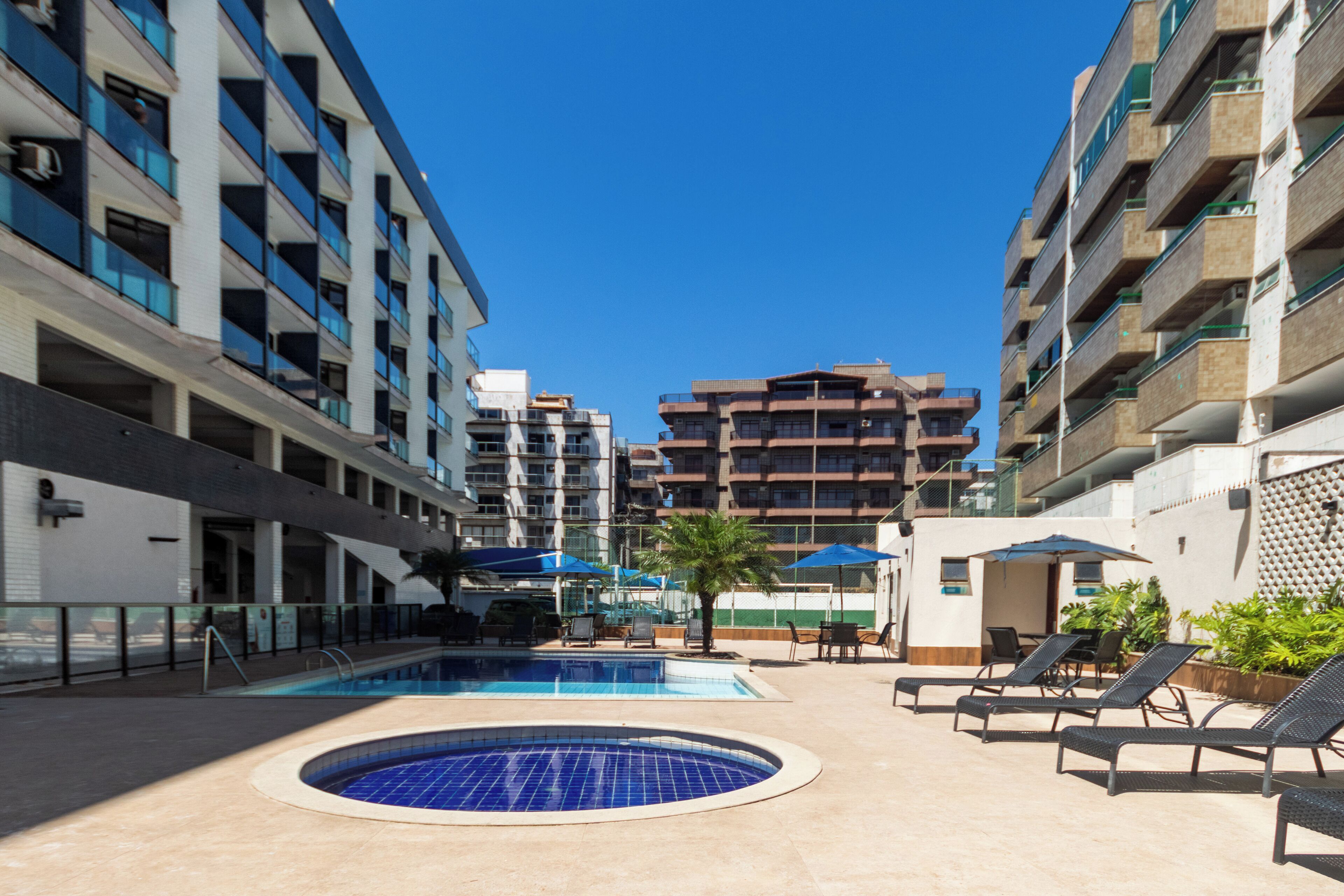 Ein Hotelpoolbereich mit rundem Pool, Liegestühlen und Sonnenschirmen.