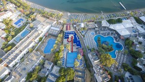 Vue aérienne d’un complexe hôtelier doté de plusieurs piscines, d’une plage et d’un port de plaisance.
