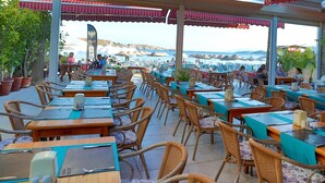 Un restaurant en bord de mer, doté d’une terrasse avec des tables et des chaises, offrant une vue sur la mer.