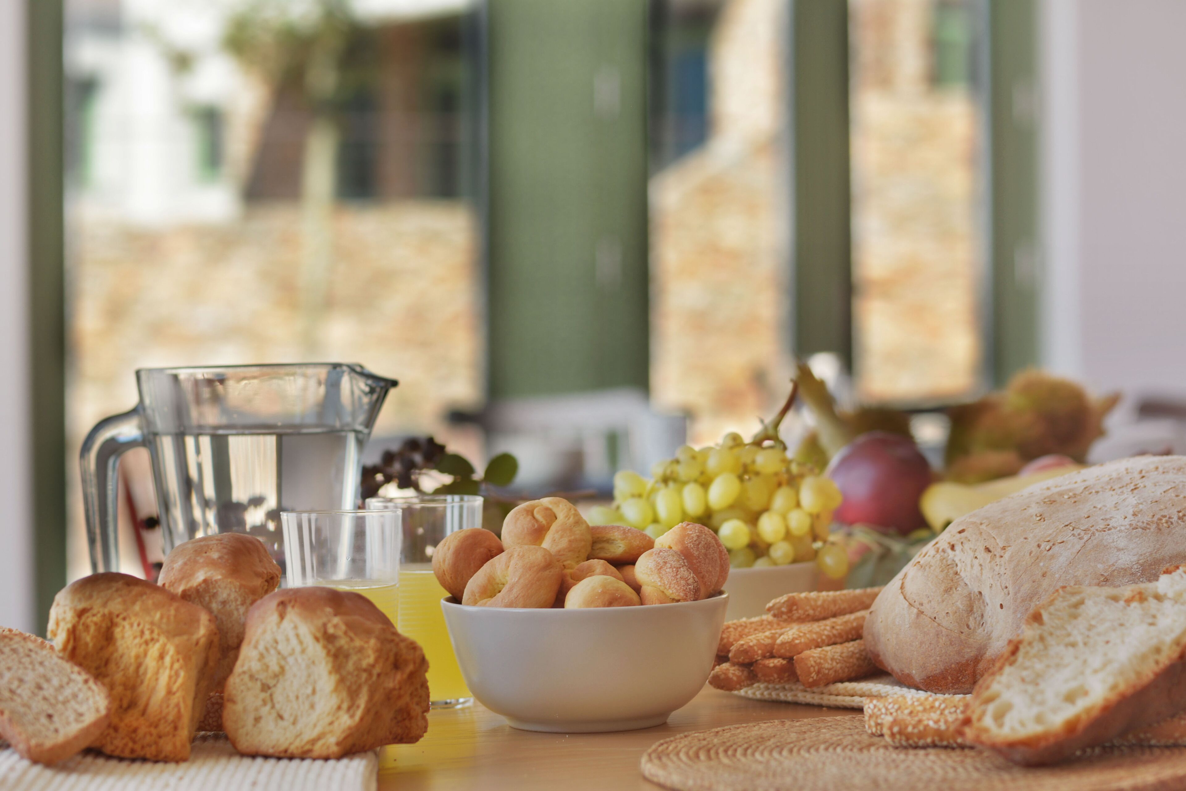 Uma mesa com pão, uvas e um jarro de suco.