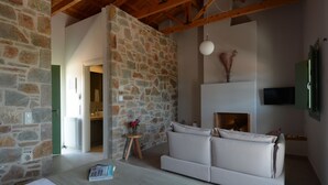 Ein Zimmer mit Steinwand, einem weißen Sofa, einem kleinen Tisch mit einer Vase und einem Kamin.