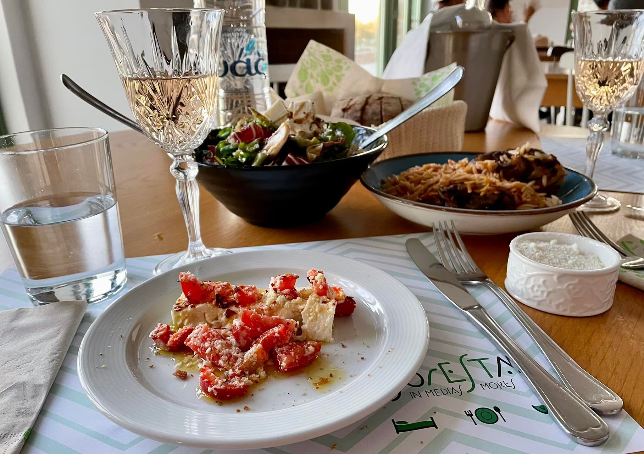A dining table with plates of food, glasses of water, and a menu.
