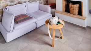 Ein gemütliches Wohnzimmer mit Steinwand, weißem Sofa, kleinem Holztisch und Kamin.