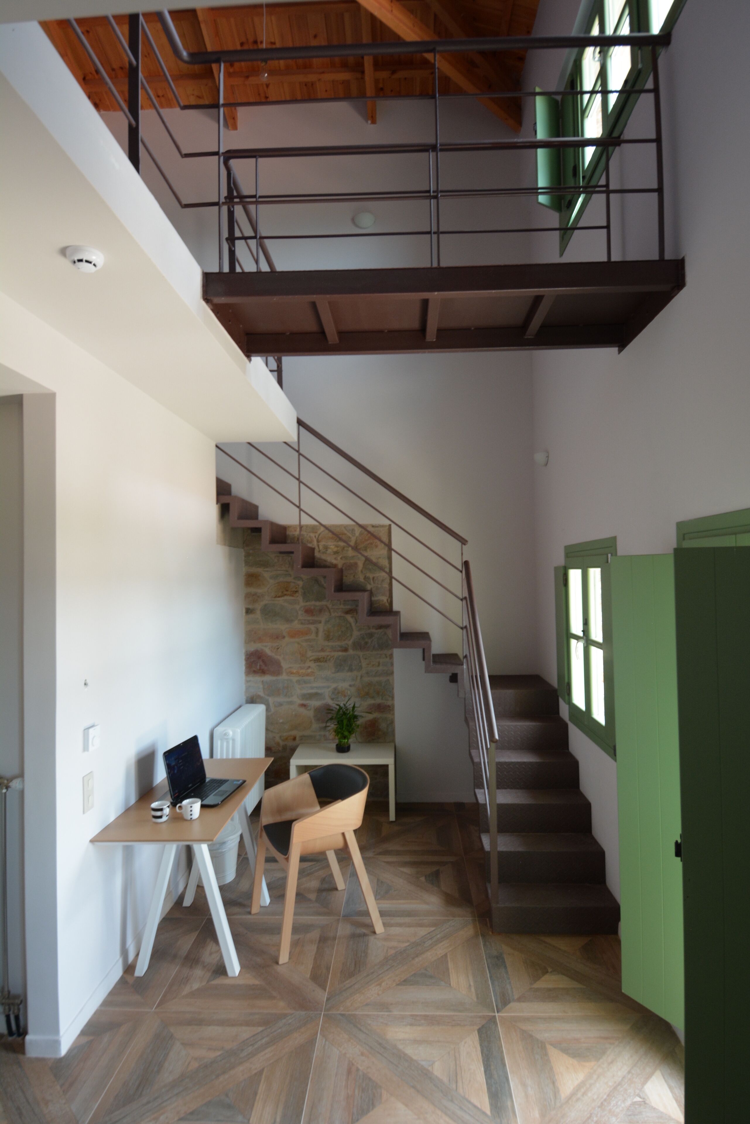 A modern interior with a staircase, a desk with a laptop, and a chair.