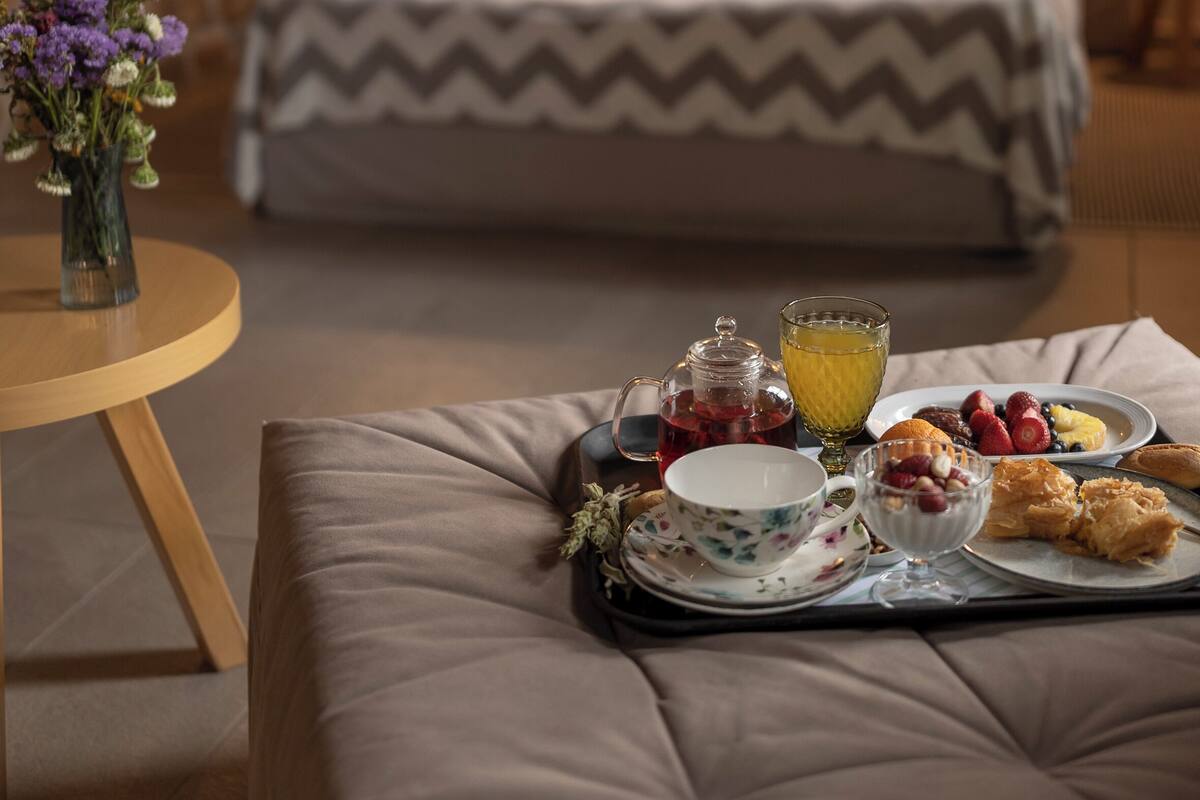 A bedroom with a bed, bedside table, and a tray with breakfast items.