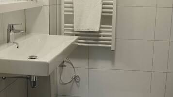 A bathroom with a white sink, a towel rack, and a shower area.