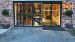 A modern building entrance with glass doors, a staircase, and brick walls. - De Kastanjefabriek (Eibergen)