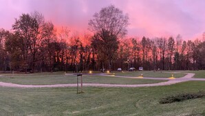 A park with pathways, benches, and trees under a pink sky. - De Kastanjefabriek (Eibergen)