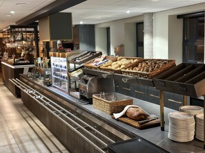 A buffet area with various food items, including bread and pastries, and a coffee machine. - De Kastanjefabriek (Eibergen)