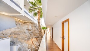 Un couloir étroit, avec un mur en pierre d’un côté et un plancher en bois de l’autre, qui mène à une porte.
