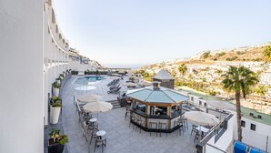 Un bar situé sur le toit d’un immeuble, avec une piscine, des places assises en plein air et une vue sur la ville.