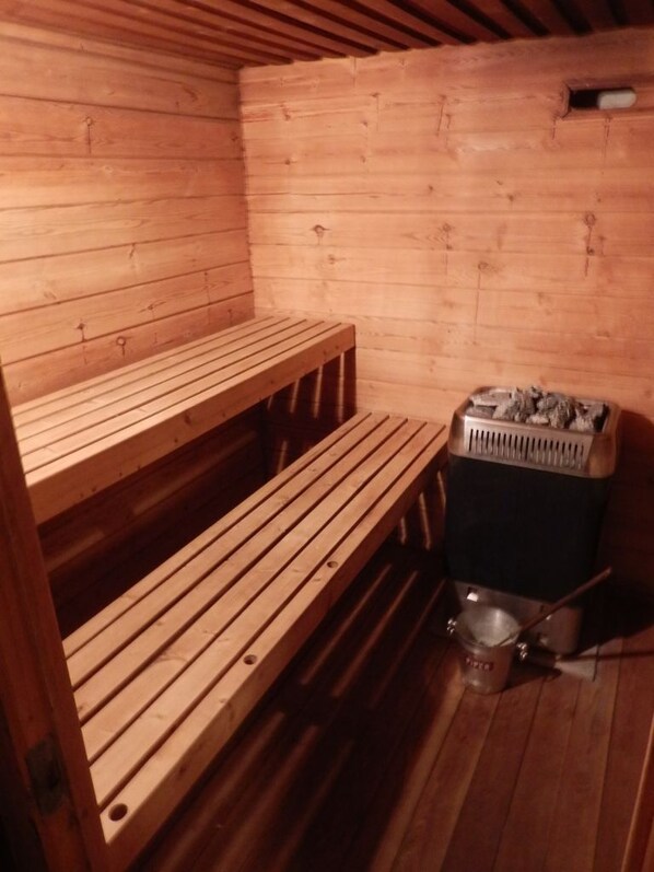 Una sauna con bancos de madera y un calentador.