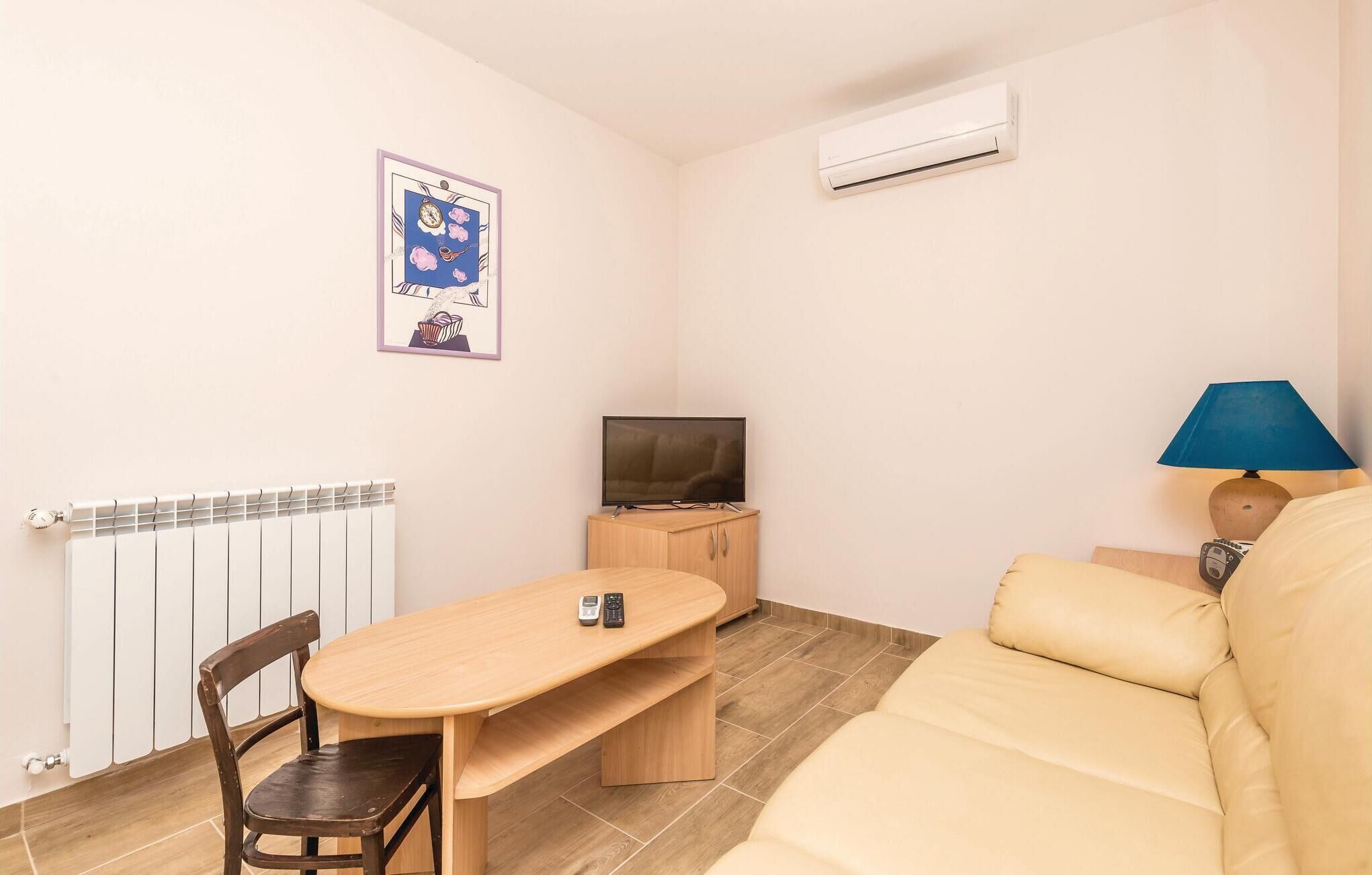 Une petite pièce agréable, avec une table en bois, un canapé, un téléviseur et une lampe.