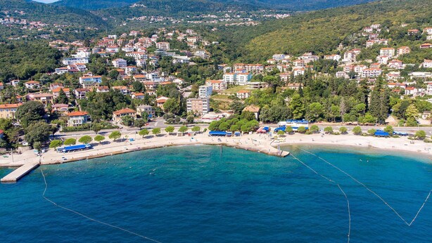 Eine Küstenstadt mit Strand, Gebäuden und Bergen im Hintergrund.